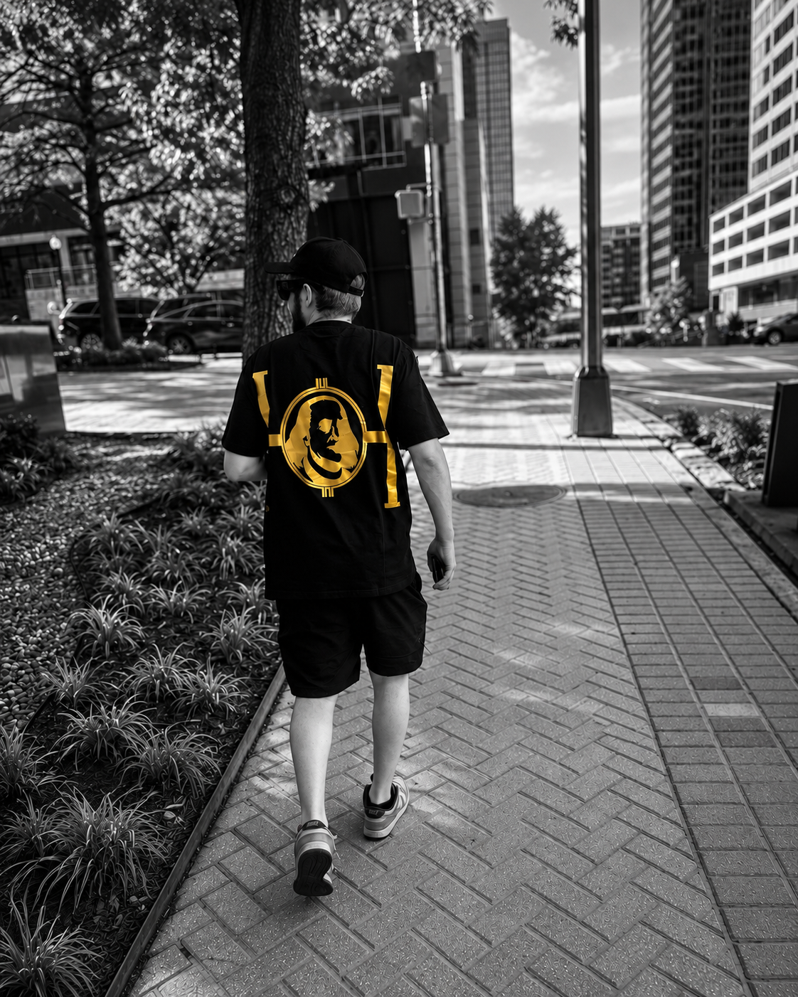 Gold Hustle Franklins back logo on a black tee during a city walk.